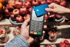 a person holding a cell phone in front of a pile of fruit
