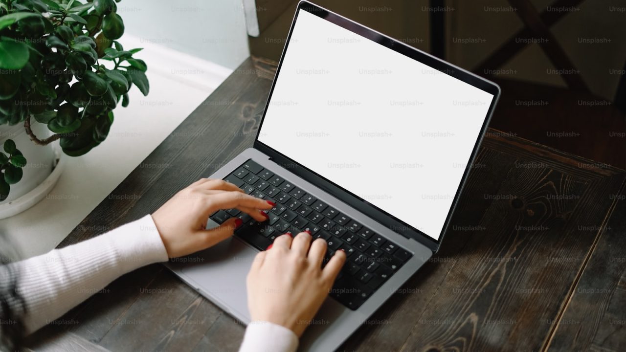 a person typing on a laptop on a wooden table
