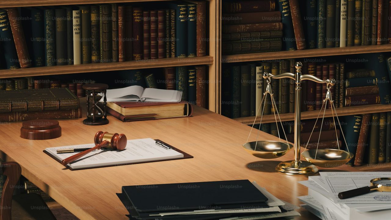 a wooden desk topped with books and a judge's scale
