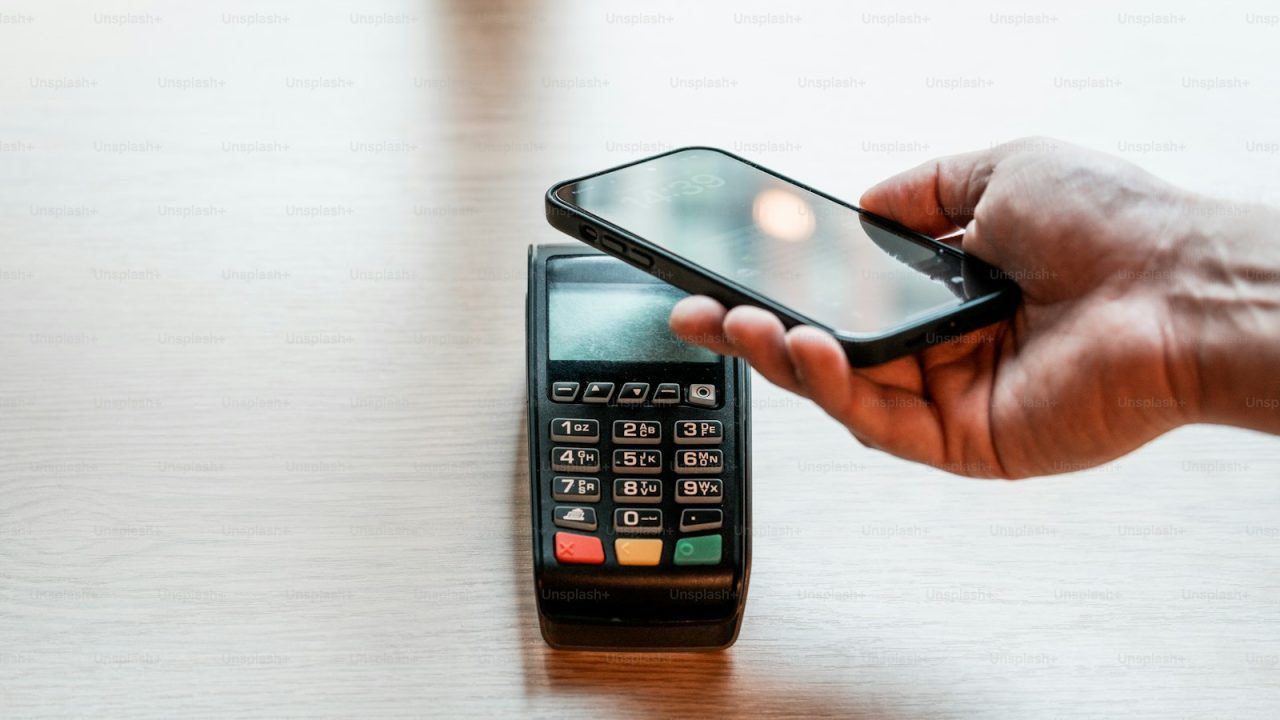 a person holding a cell phone on top of a wooden table