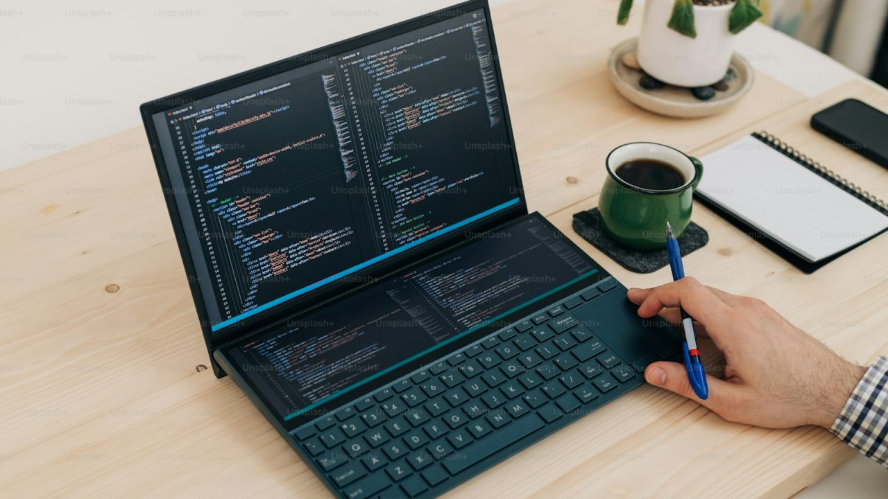 a person is writing on a laptop on a desk