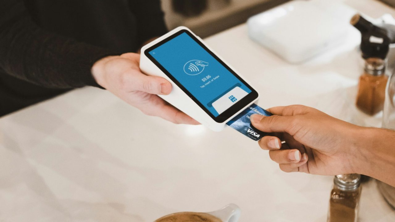 Customer paying with a credit card at a point of sale terminal showing how surcharging works in 2026