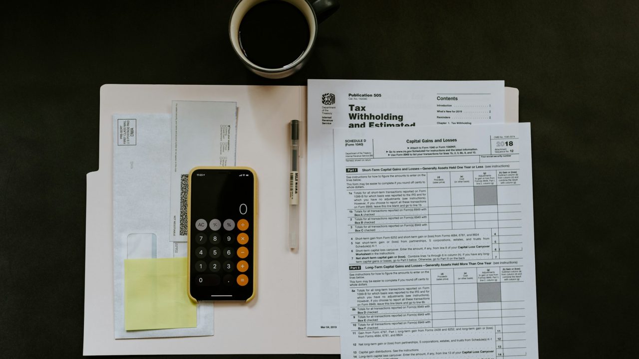 Merchant reading a credit card processing statement with calculator and pen analyzing fees